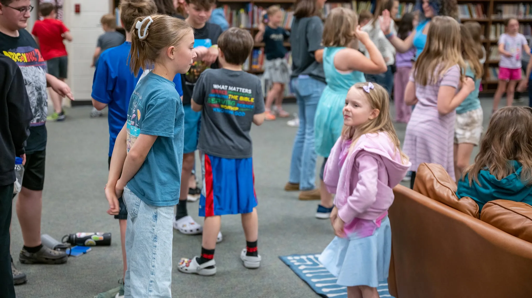 Students of several ages standing and talking together in the school media centre