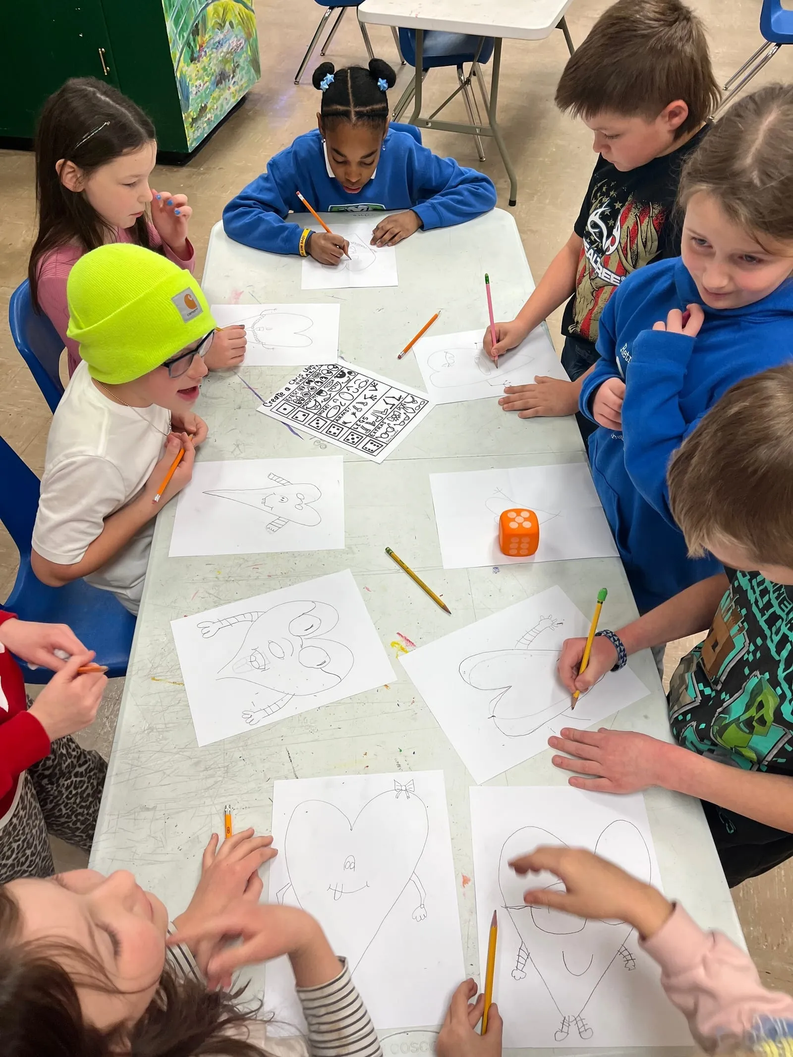 Looking down on a long table ringed with students, each drawing on their own sheet of paper