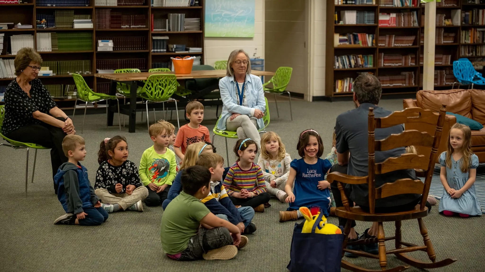 A small group of students seated on the floor with two teachers in the school library