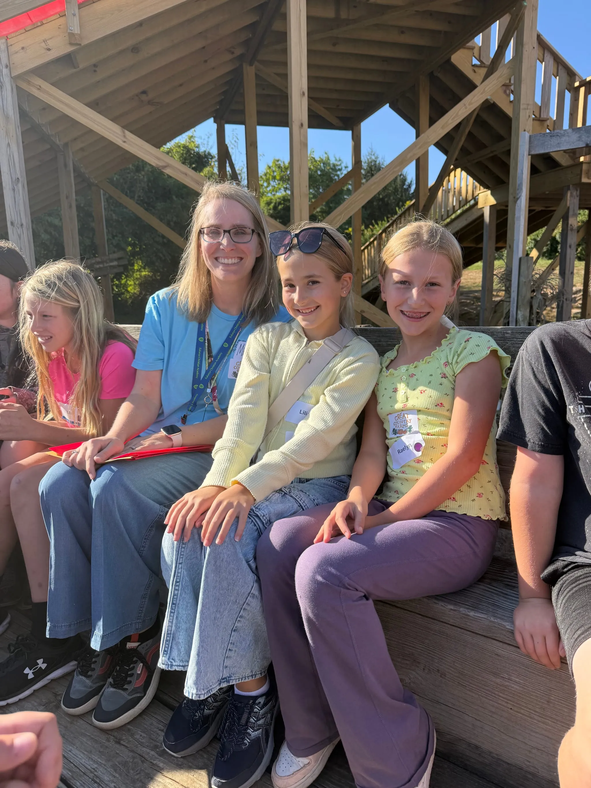 A teacher sitting on the playground steps with four of her students on a bright afternoon