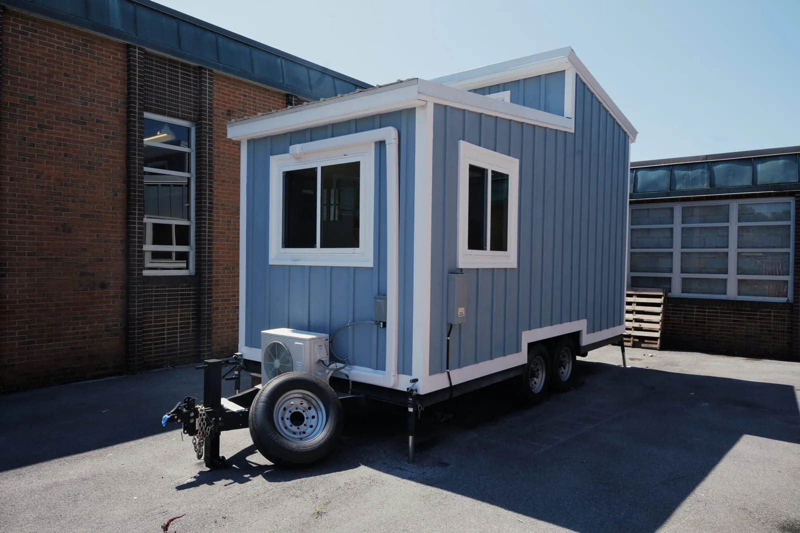 The nineteen-foot tiny house students framed, wired and finished, parked on its trailer outside the school